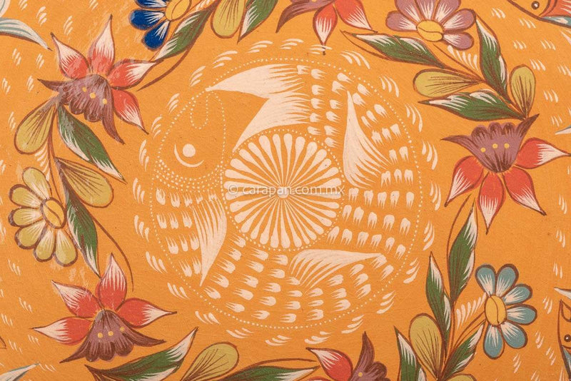 Light orange dish with curvy flower shape decorated with two circles of fishes painted in green and dark orange following by a circle of flowers and one  fish in beige at the center with its mouth near its tail in circular position. Finally, a star in beige with a white dot and strokesat the center