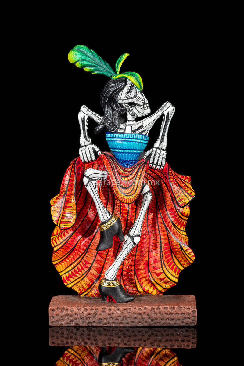 Day of the Dead Wooden Sculpture Mexican Catrina dancing can can lifting up her skirt she wears 3 feather haad dress, an orange skirt & a blue top her clothes are decoraated with zapotec symbols & the skeleton is meticulously decorated with patterns in black & White