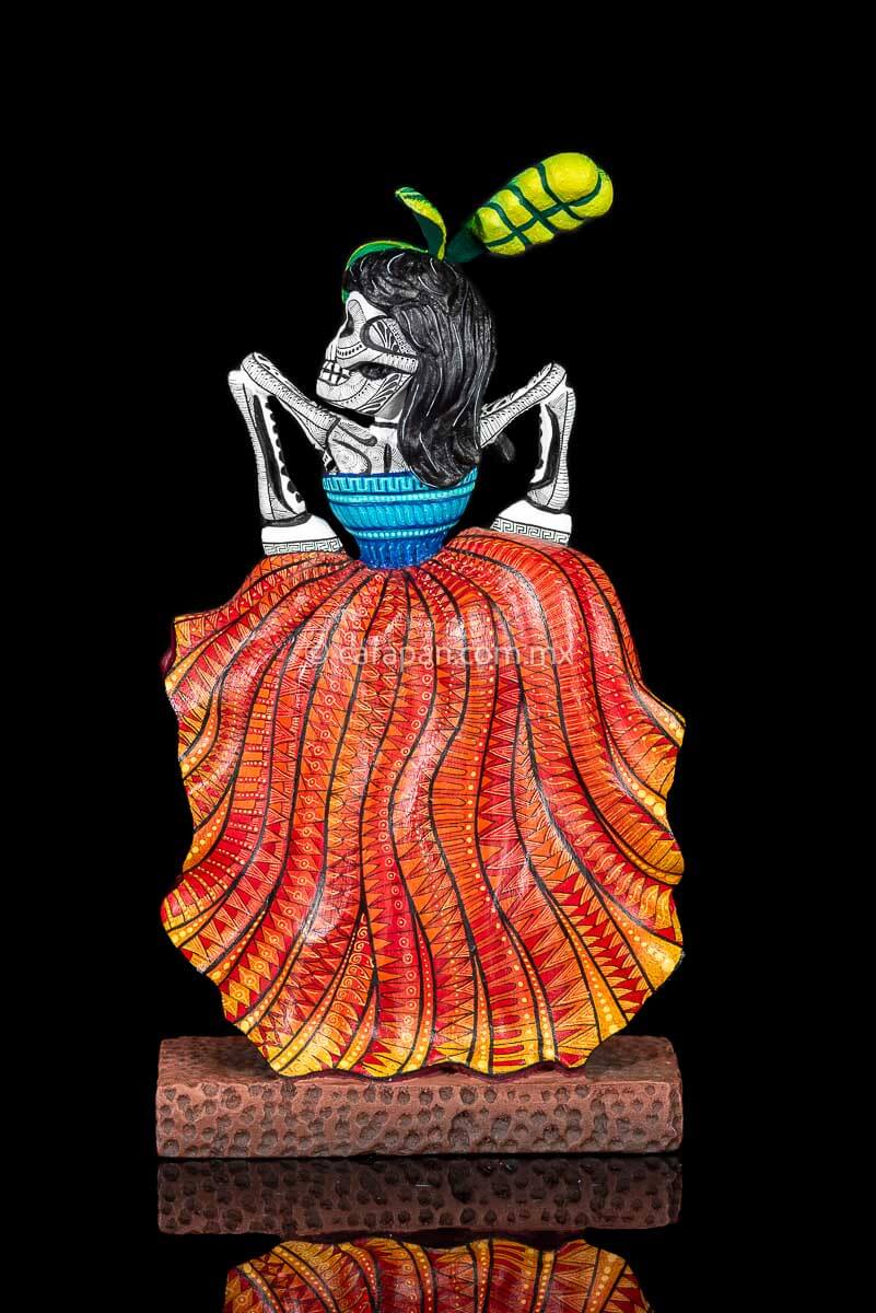 Day of the Dead Wooden Sculpture Mexican Catrina dancing can can lifting up her skirt she wears 3 feather haad dress, an orange skirt & a blue top her clothes are decoraated with zapotec symbols & the skeleton is meticulously decorated with patterns in black & White