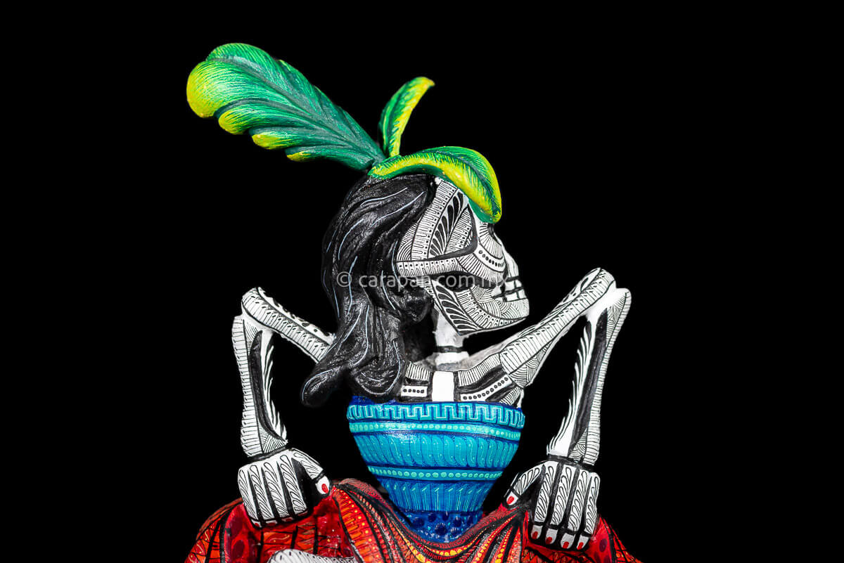 Day of the Dead Wooden Sculpture Mexican Catrina dancing can can lifting up her skirt she wears 3 feather haad dress, an orange skirt & a blue top her clothes are decoraated with zapotec symbols & the skeleton is meticulously decorated with patterns in black & White