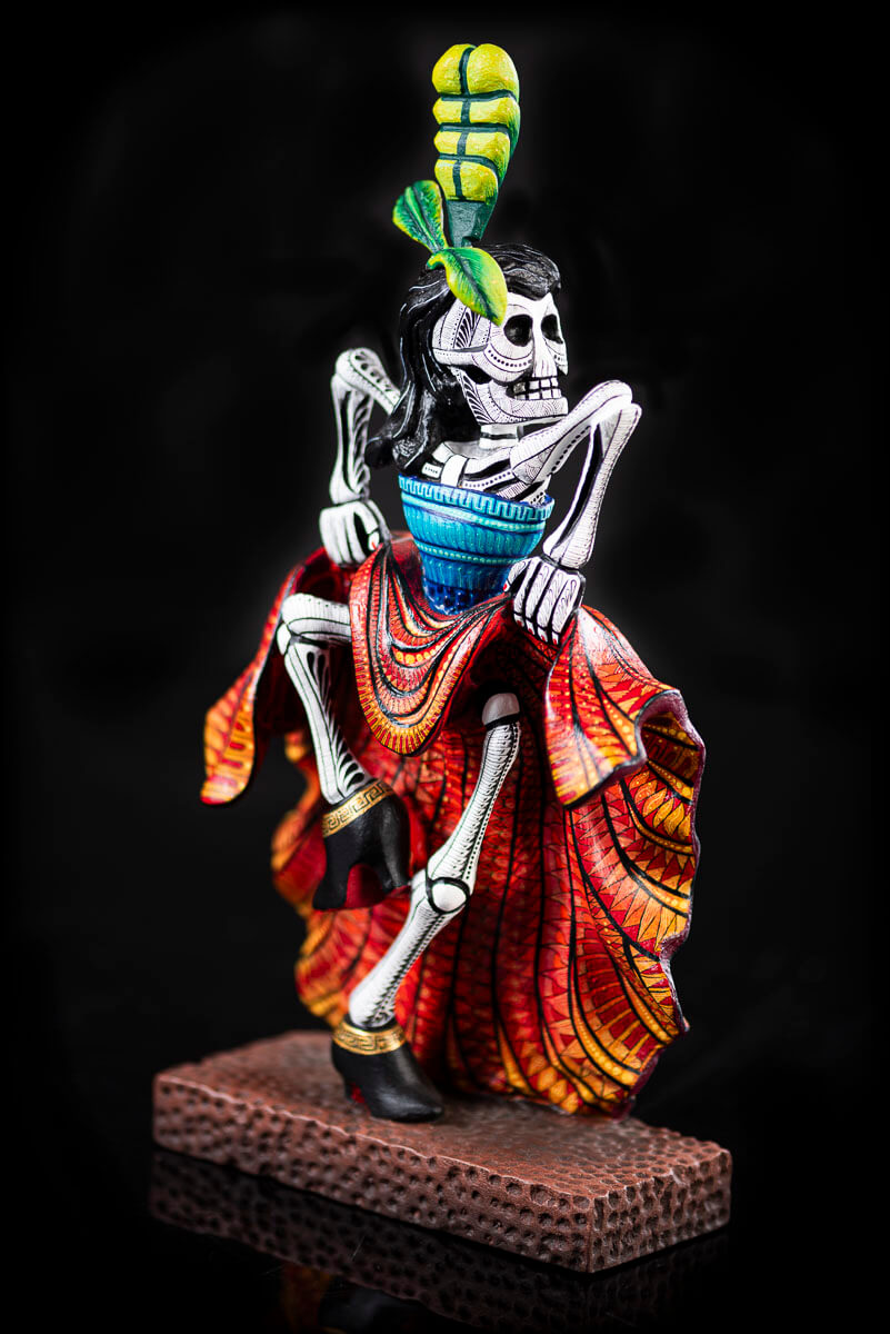 Day of the Dead Wooden Sculpture Mexican Catrina dancing can can lifting up her skirt she wears 3 feather haad dress, an orange skirt & a blue top her clothes are decoraated with zapotec symbols & the skeleton is meticulously decorated with patterns in black & White