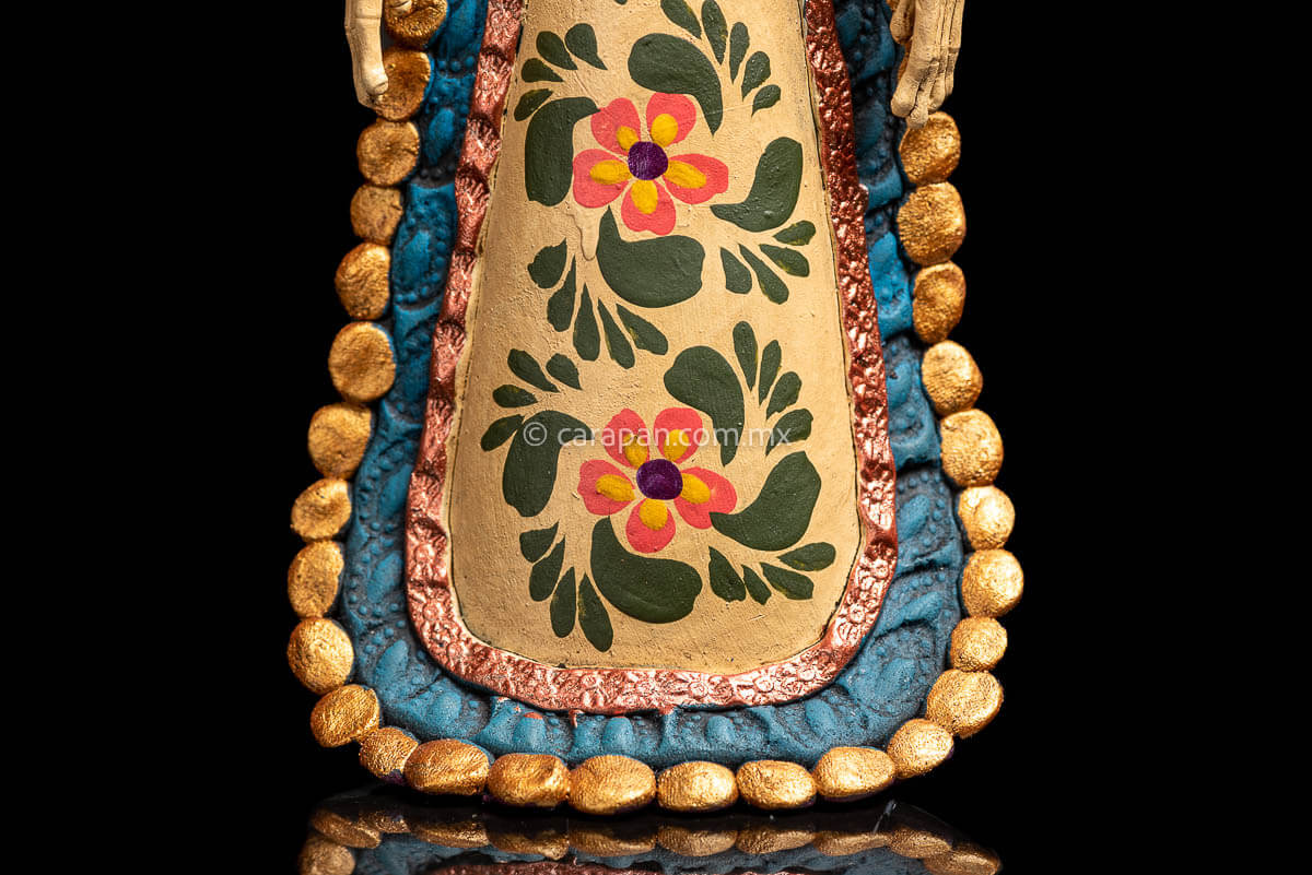 Mexican Clay Catrina carrying stick on her back with Fish and Butrerflies her skull is decorated with blue and red strokes and her dress has hand painted flowers dress