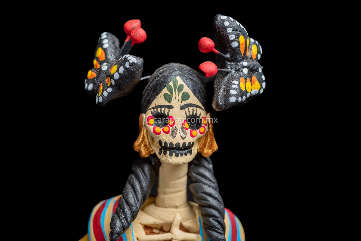 Mexican catrina with monarch butterflies her forehead is painted with green strokes and her eyes with yellow petals with red contour she also carries a rebozo around her neck Head