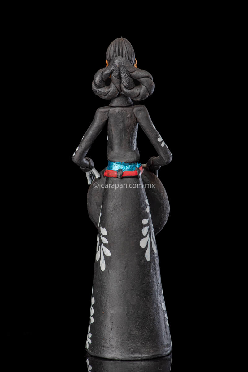 Catrina day of the dead Clay Sculpture dressed in a black and white charro dress  holding her hat on  her waist  with both hands.  Her skull is  hand painted.  back