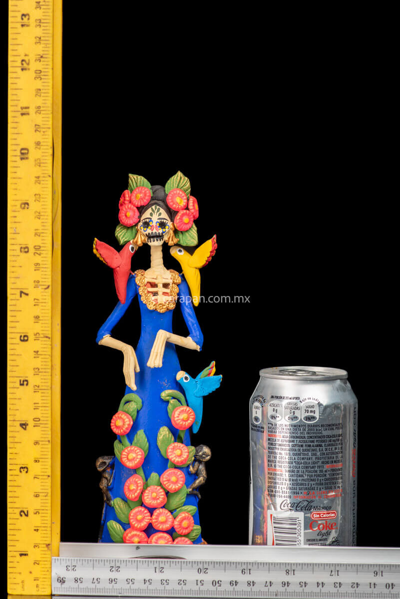 Mexican Clay Catrina Sculpture with blue dress and pink flowers. The catrina is inspired by Two of the most emblematic Frida Kahlo's self portraits with monkeys and parrots. Taht's why this catrina has three parrots and monkeys next to her. Her head dress is decorated with pink flowers and her skull is hand painted.