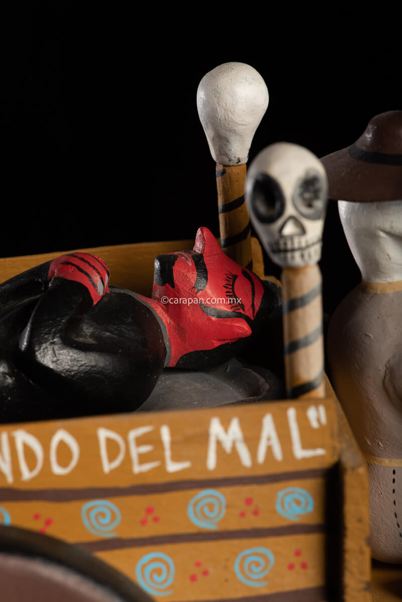 Cart pulled by a brown mule with 1 skeleton as rider & a figure representing the dead on it beside a death devil. The cart displays the legend in spanish that states "saving the world from evil" on one side & "Death's cart driver on the other side"