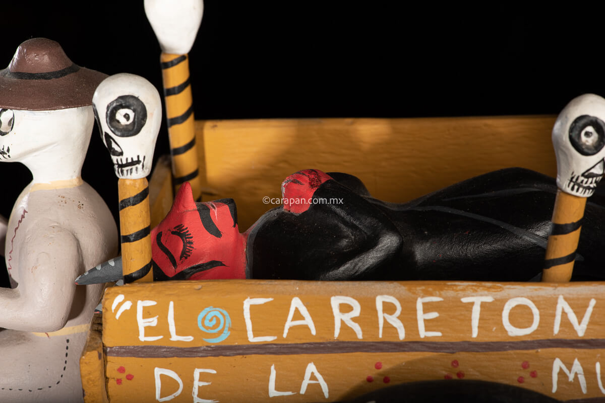 Cart pulled by a brown mule with 1 skeleton as rider & a figure representing the dead on it beside a death devil. The cart displays the legend in spanish that states "saving the world from evil" on one side & "Death's cart driver on the other side"