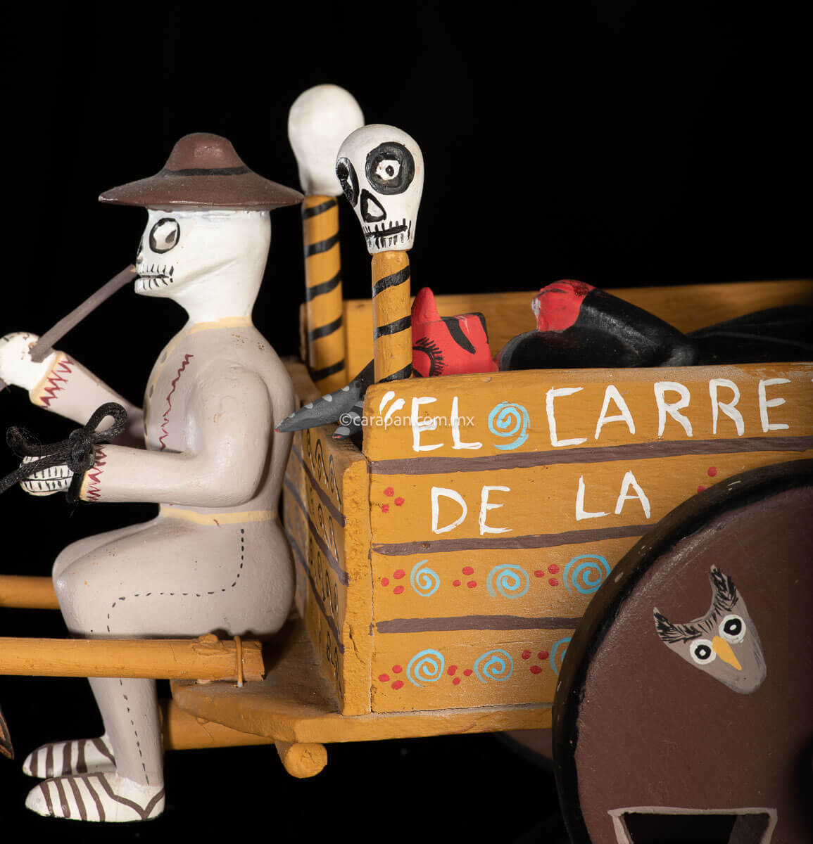 Cart pulled by a brown mule with 1 skeleton as rider & a figure representing the dead on it beside a death devil. The cart displays the legend in spanish that states "saving the world from evil" on one side & "Death's cart driver on the other side"