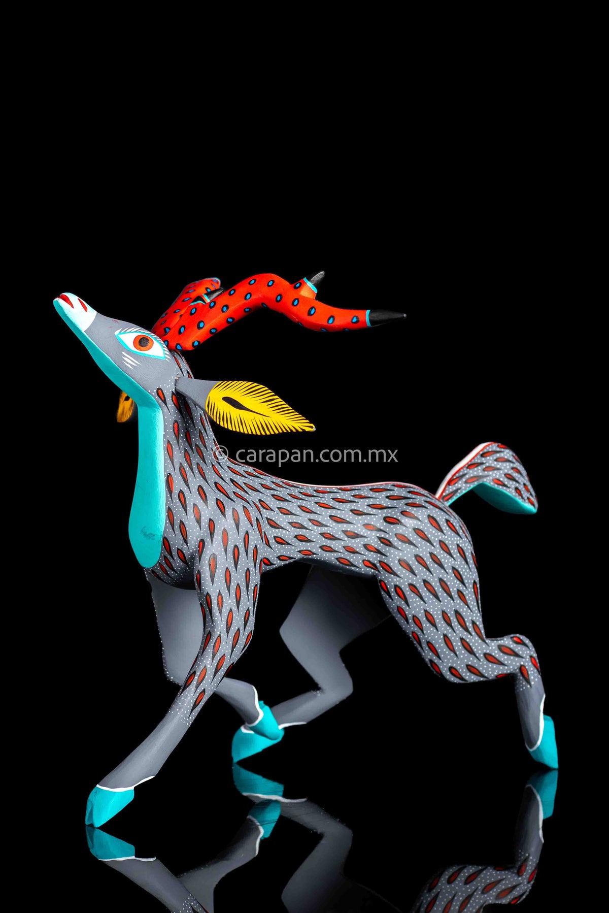 Mexican wood carving of a deer painted in gray with red strokes & white dots