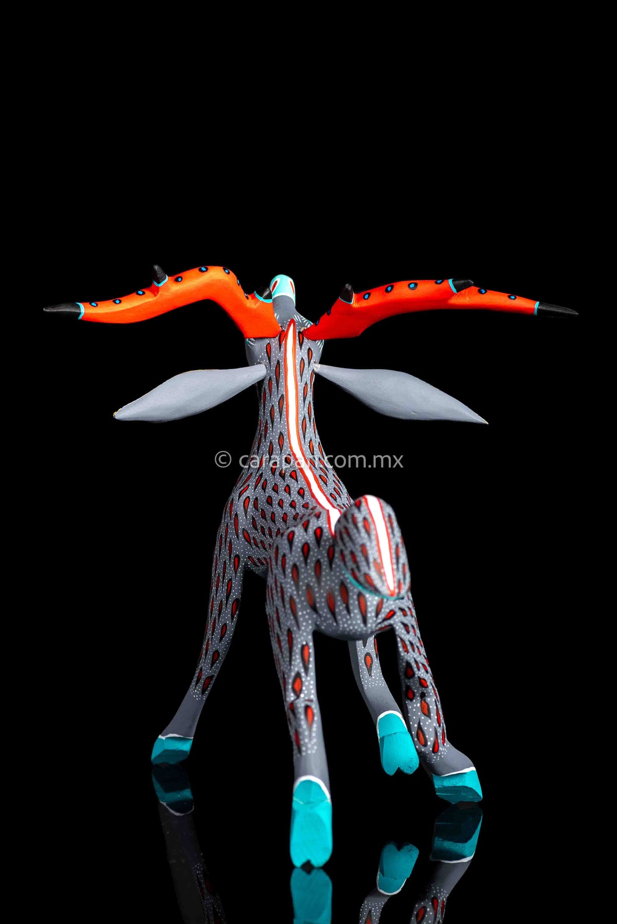Mexican wood carving of a deer painted in gray with red strokes & white dots