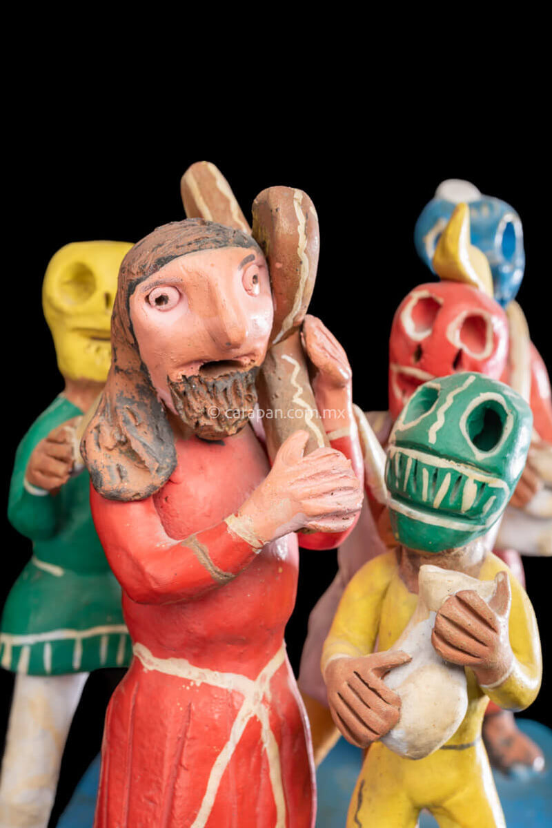 Jesus Carrying the cross escorted by 4 men wearing skull masks