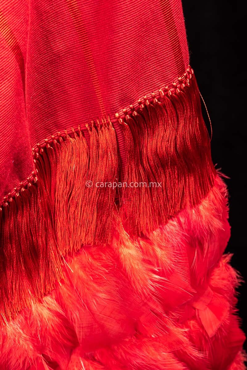 Detail of Backstrap loomed open poncho in red with feathered fringe.