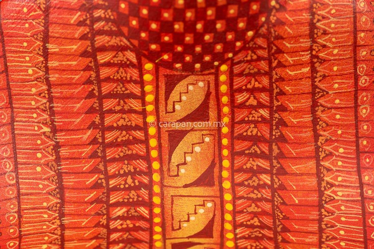 Wooden cobra hand carved from a single block of copal wood in Oaxaca Mexico, decorated with a fine pattern of zapotec symbols in a predominant orange tone