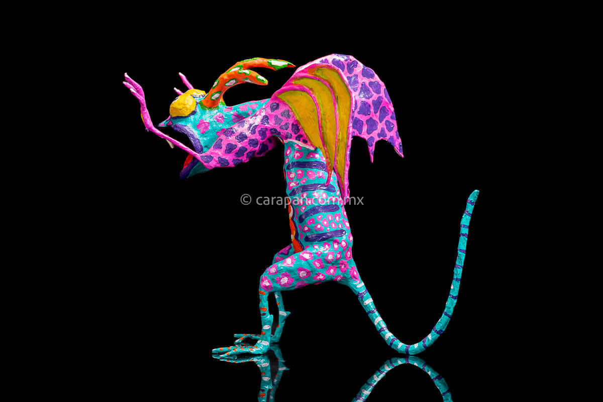 User  Please create a selling description for Paper Mache Alebrije Dragon Style Standing with hands up and mouth open showing 2 fangs popping yellow eyes and two orange horns. His body is painted in turquoise with pink dots and blue stripes and his wings are yellow outlined in pink