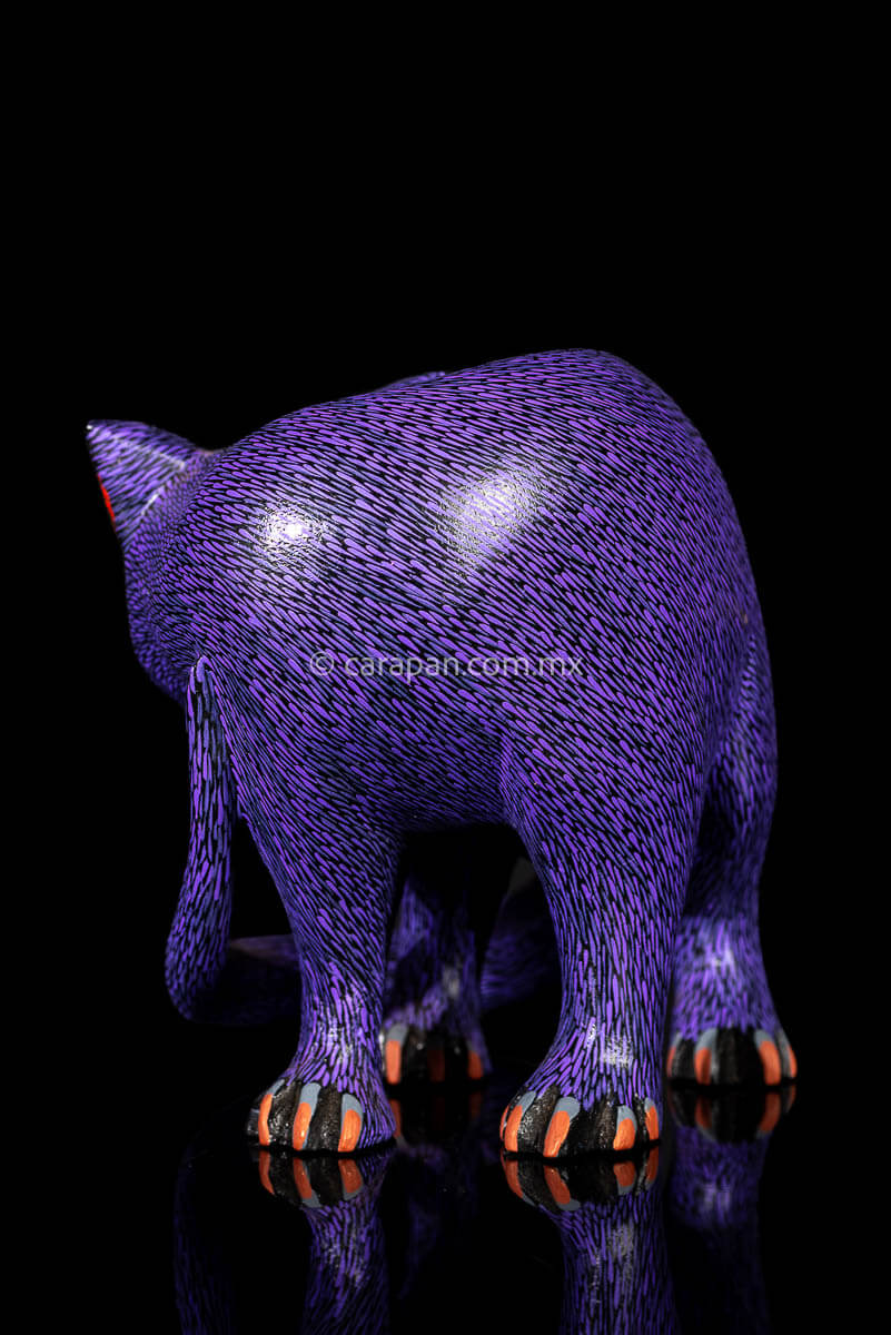 Mexican Wooden Sculpture of a purple cat looking backwards with delicate black strokes that resemble fur carved from a single block of wood