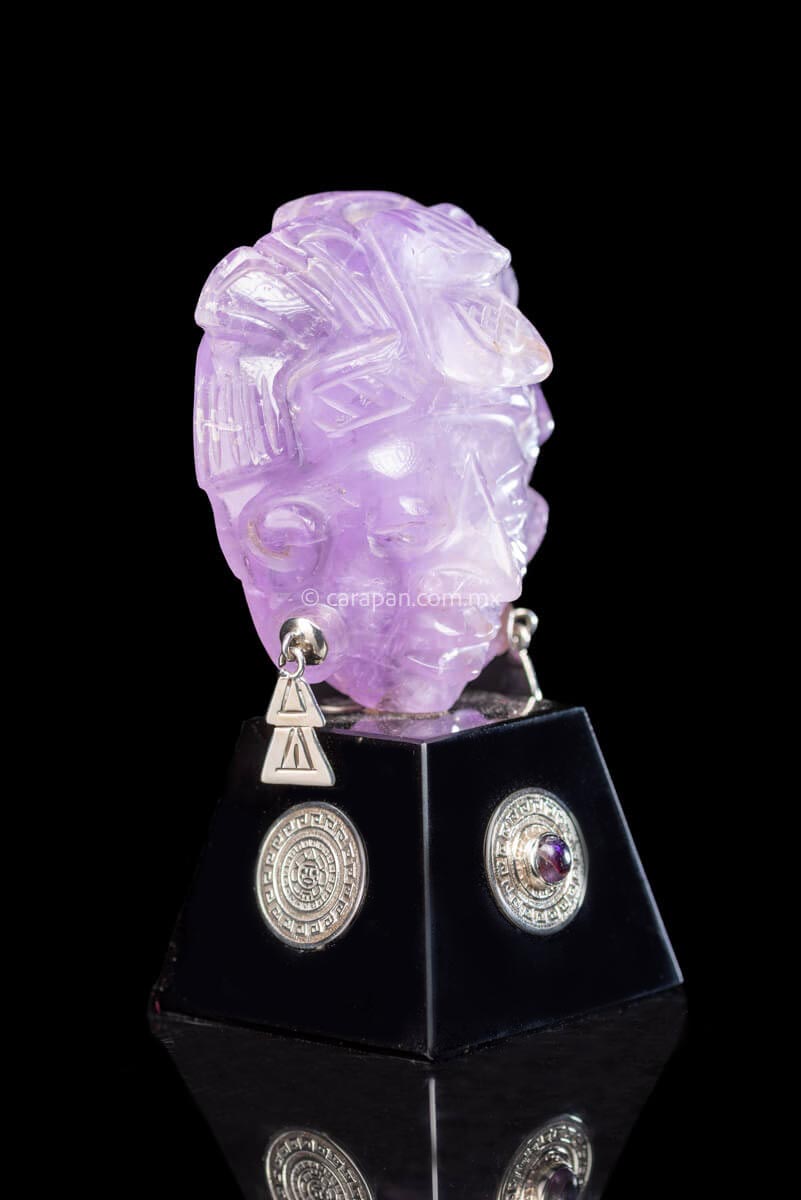 Amethyst sculpture Mayan Character wearing head dress and earrings. The base is made of obsidian and has a silver medallion with the Aztec Calendar on two sides and a Chimalli  on the other two