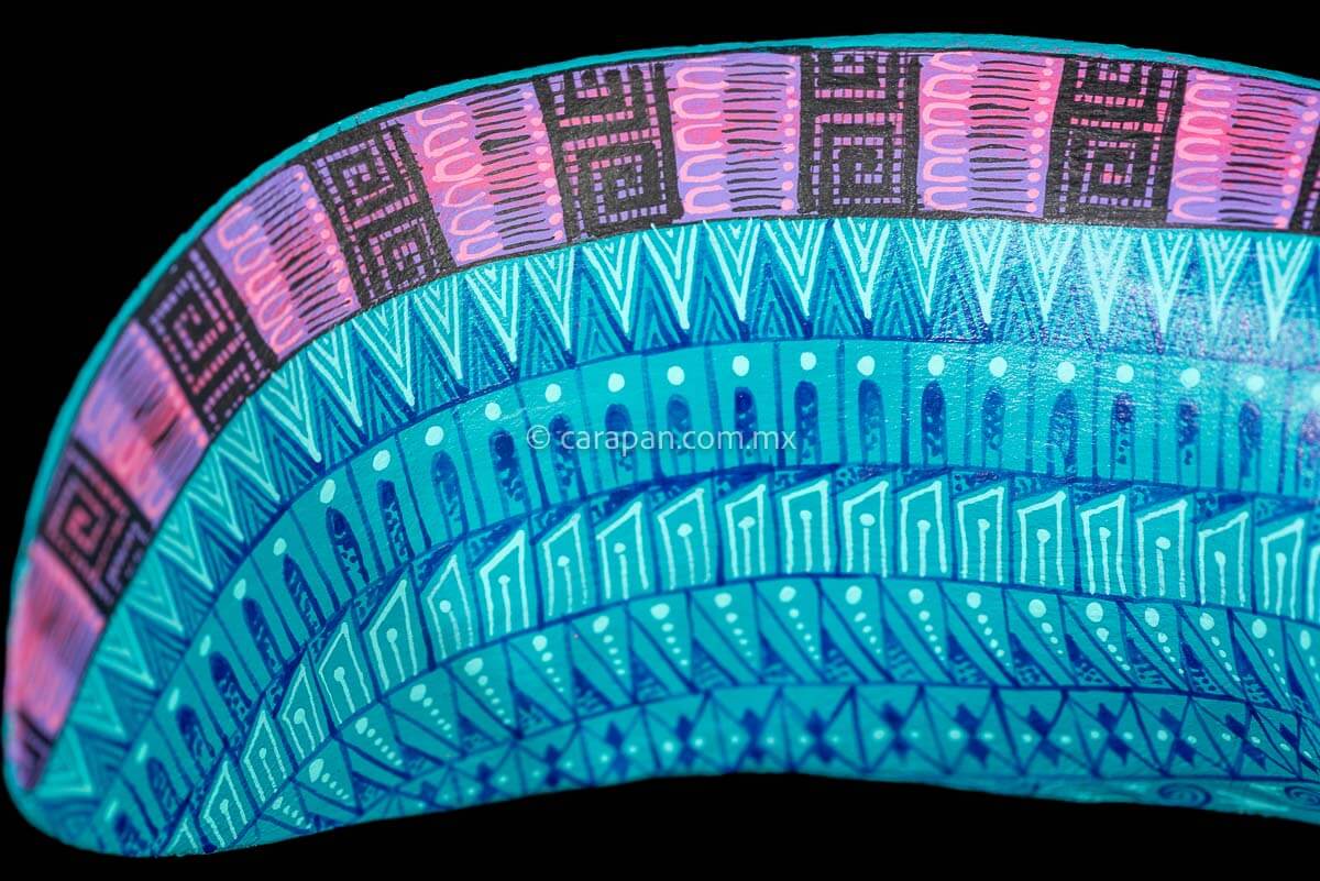 tail of Axolotl Wood Carving from Oaxaca decorated with zapotec symbols in turquoise & a contrast fucsia over the spine and legs 