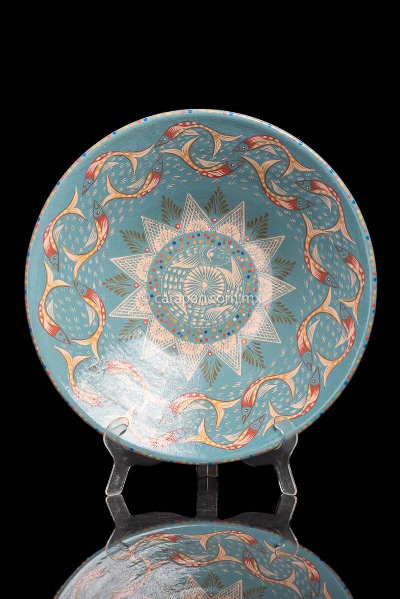 Glazed Clay Bowl with fish swimming creating a circle around a star pattern in beige over a turquoise blue pattern.