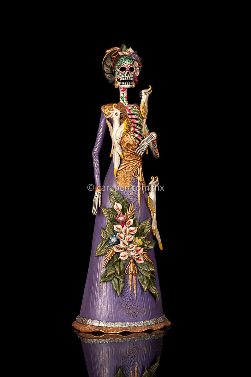 Mexican clay catrina, day of the dead sculpture with parrots and purple dress.