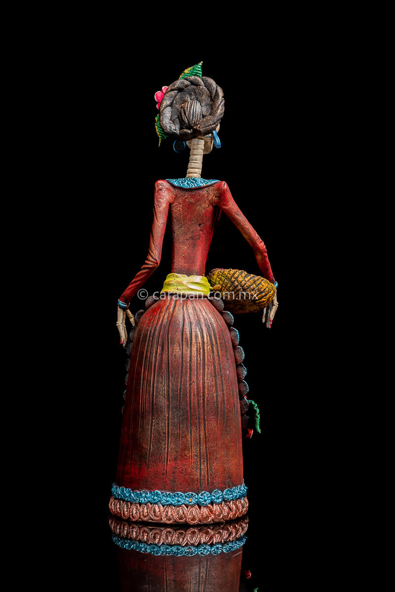 Mexican Clay Catrina with bread basket and 3 pastillage flowers on her apron. She also has 3 flower on her head back