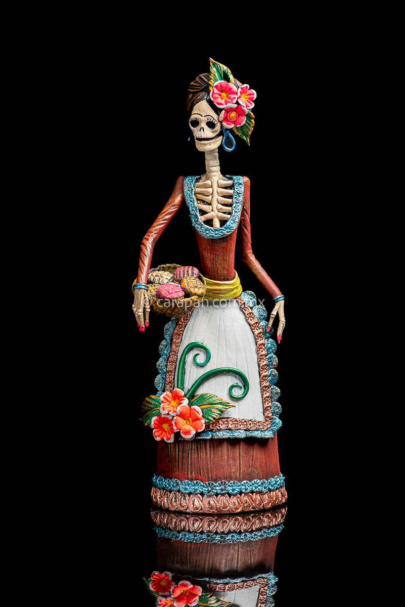 Mexican Clay Catrina with bread basket and 3 pastillage flowers on her apron. She also has 3 flower on her head