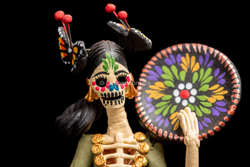 Colorful Mexican  Clay Catrina holding dish on her left hand with butterflies head dress and flowery dress  detail