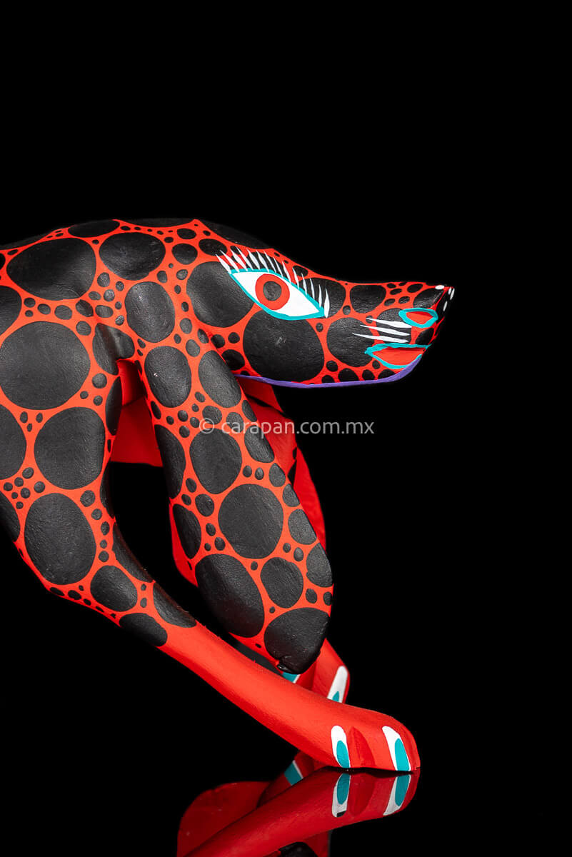 head of Alebrije Wood Carving Sculpture of walking dog in red with black round patches
