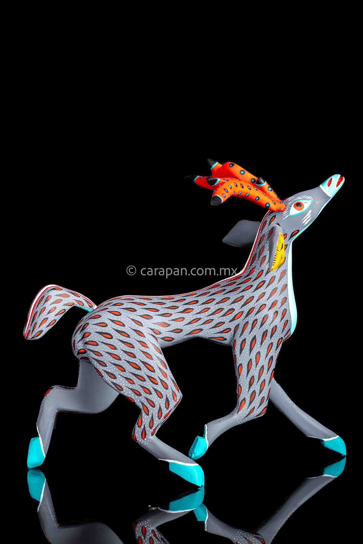 Mexican wood carving of a deer painted in gray with red strokes & white dots
