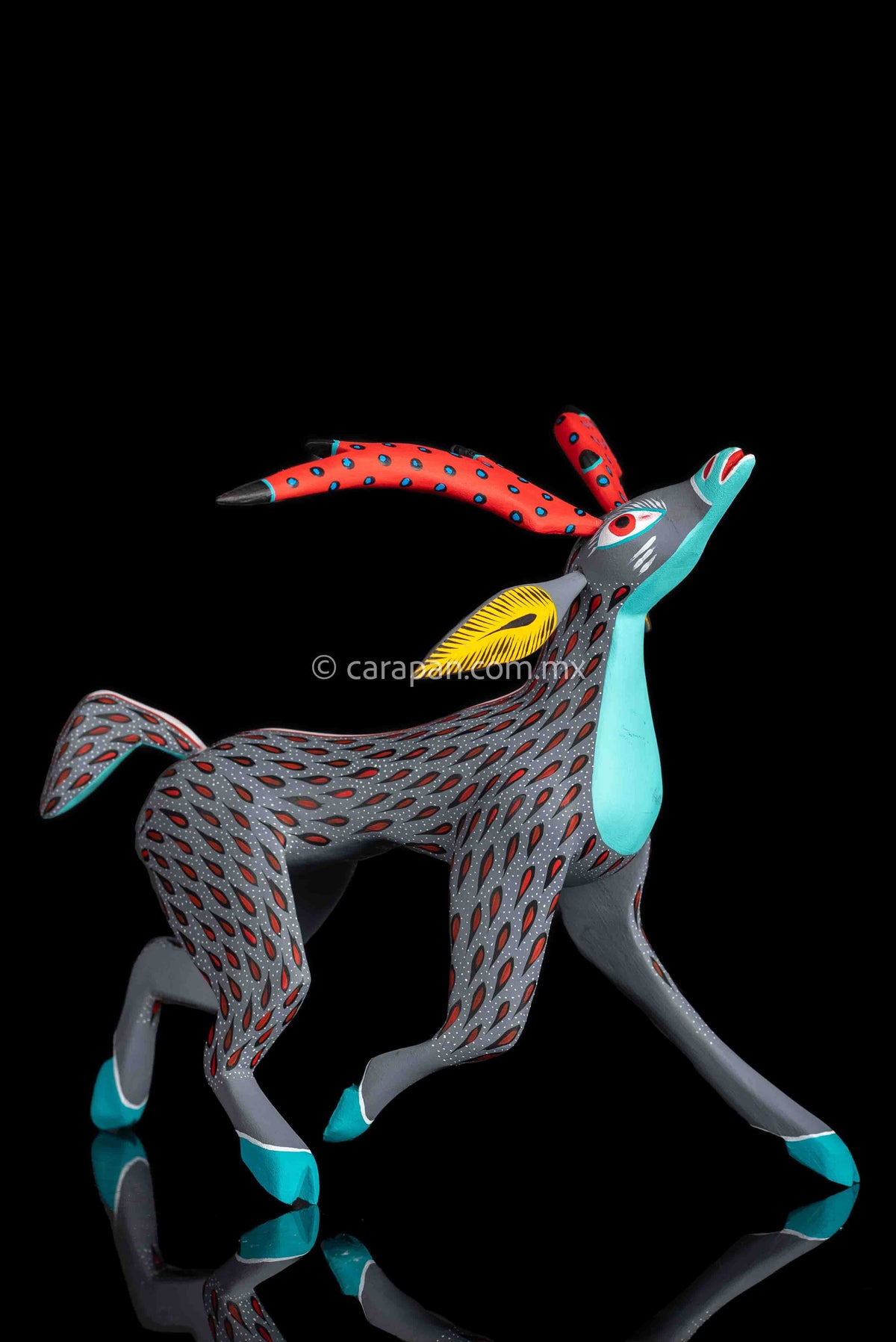 Mexican wood carving of a deer painted in gray with red strokes & white dots