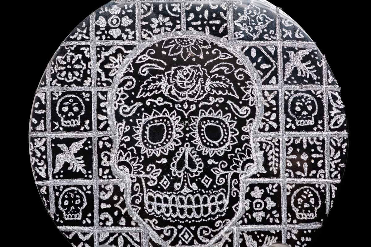 Skull decorated with vegetal motifs over a tile background with birds, flowers and skulls