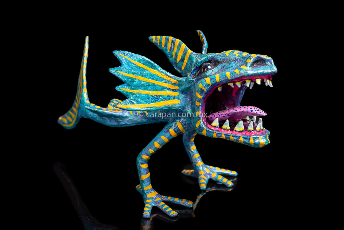 Paper Mache Alebrije inspired by sharks in teal and turquoise tones with yellow strokes, fierce open mouth showing tooth and pink tongue with blue dots. Standing on two legs 