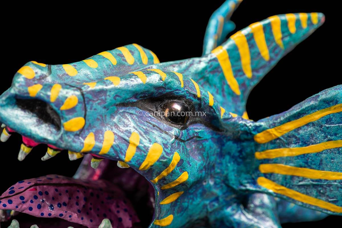 Paper Mache Alebrije inspired by sharks in teal and turquoise tones with yellow strokes, fierce open mouth showing tooth and pink tongue with blue dots. Standing on two legs 