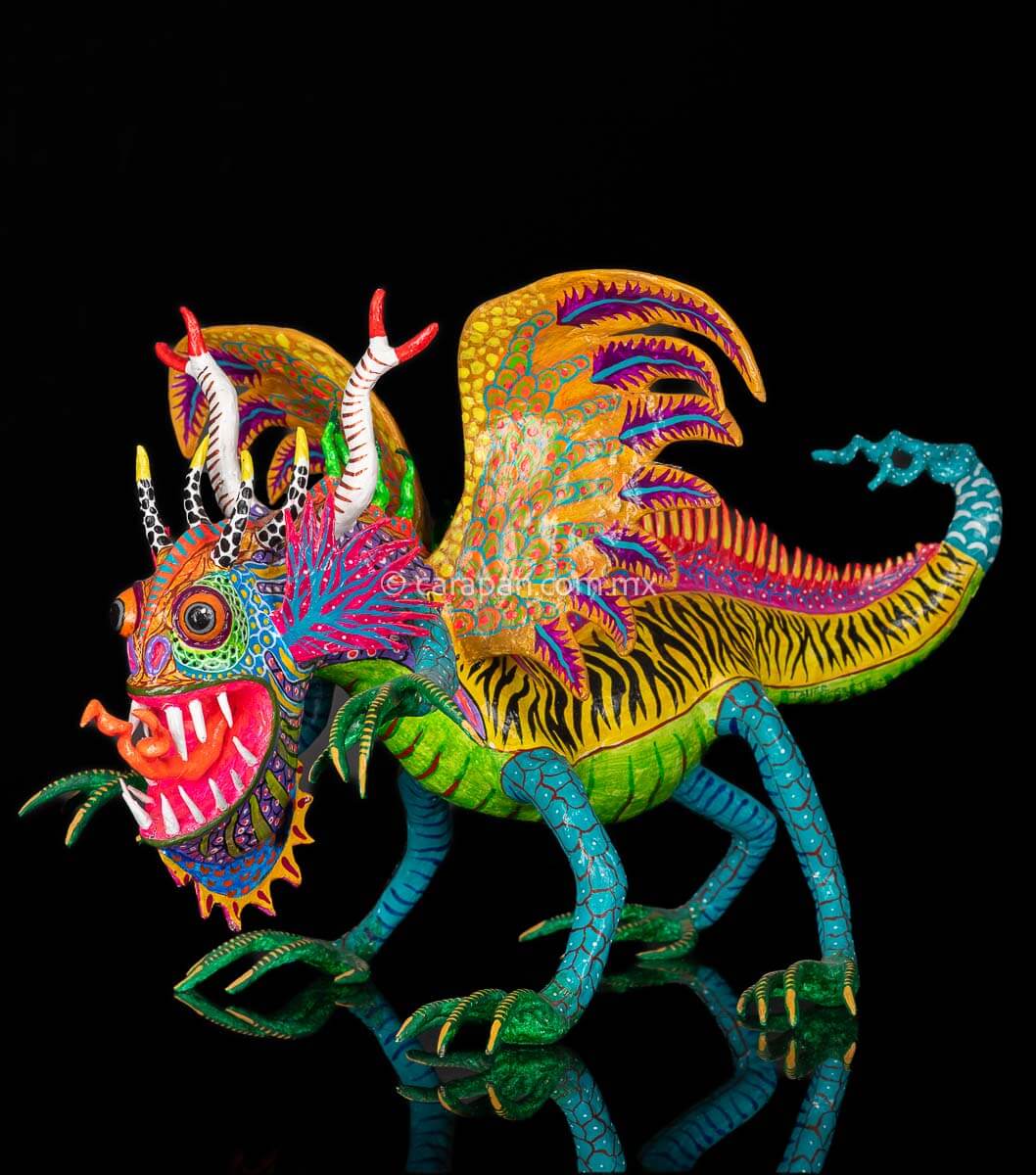 Hand Crafted Paper Mache Alebrije Mexican Dragon with orange wings, four black and white horns and two longer white  horns with red tips; fierce gaze with sharp tooth