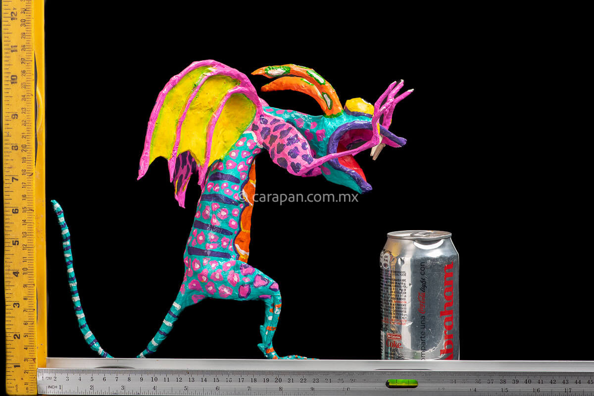User  Please create a selling description for Paper Mache Alebrije Dragon Style Standing with hands up and mouth open showing 2 fangs popping yellow eyes and two orange horns. His body is painted in turquoise with pink dots and blue stripes and his wings are yellow outlined in pink rulers
