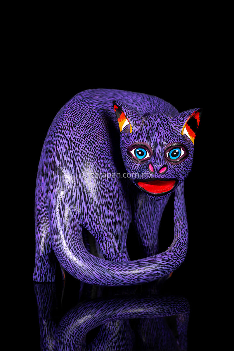 Mexican Wooden Sculpture of a purple cat looking backwards with delicate black strokes that resemble fur carved from a single block of wood