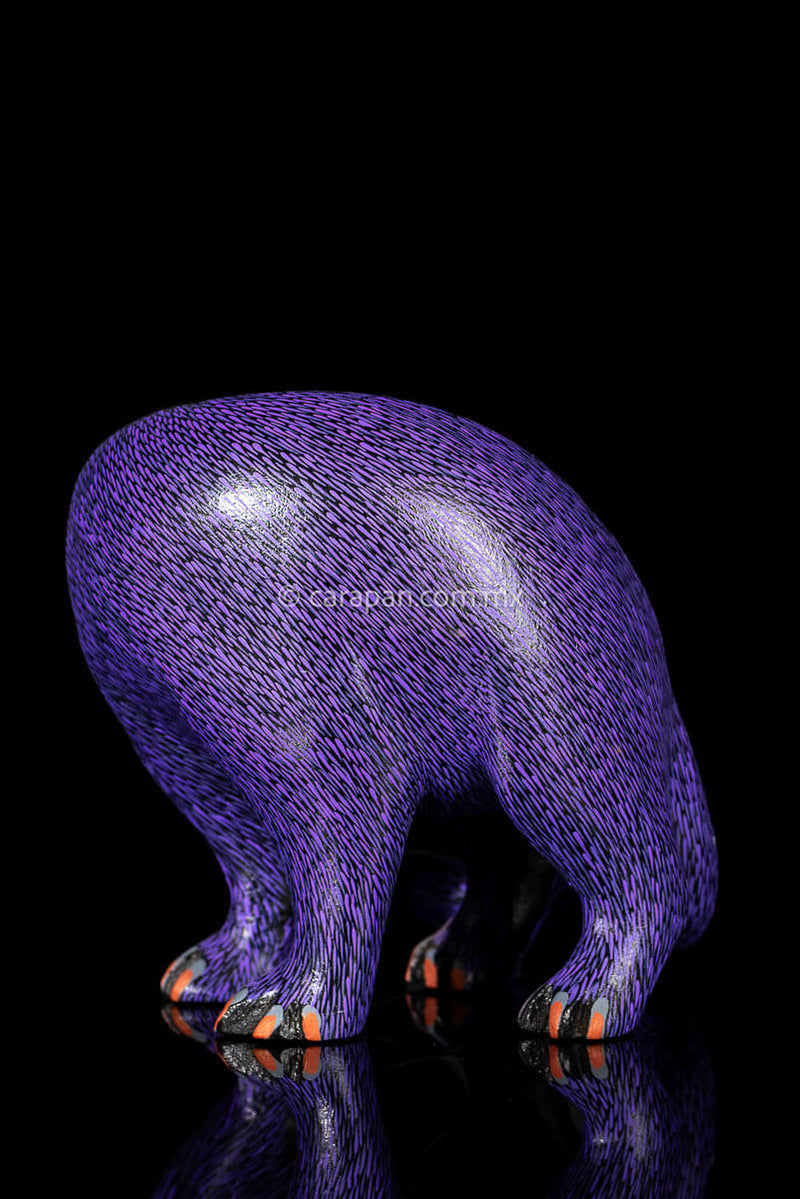 Mexican Wooden Sculpture of a purple cat looking backwards with delicate black strokes that resemble fur carved from a single block of wood