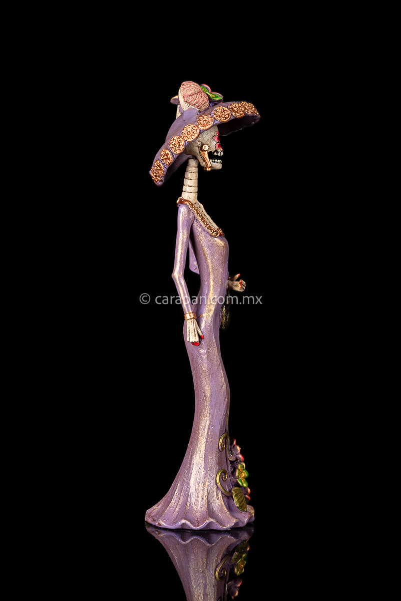 Day of the dead Sculpture, Catrina wearing a purple dress with flowers at the bottom and a traditional Posada Style hat. Crafted in Capula Michoacan Mexico