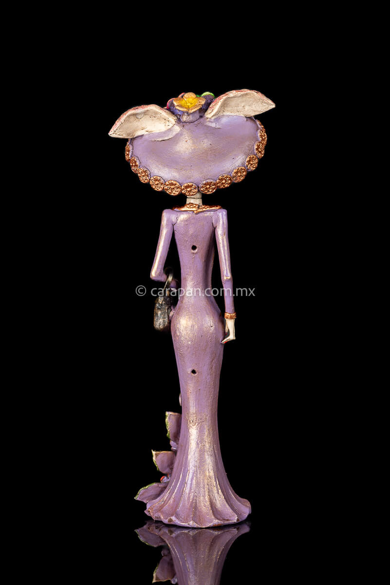 Back of Day of the dead Sculpture, Catrina wearing a purple dress with flowers at the bottom and a traditional Posada Style hat. Crafted in Capula Michoacan Mexico